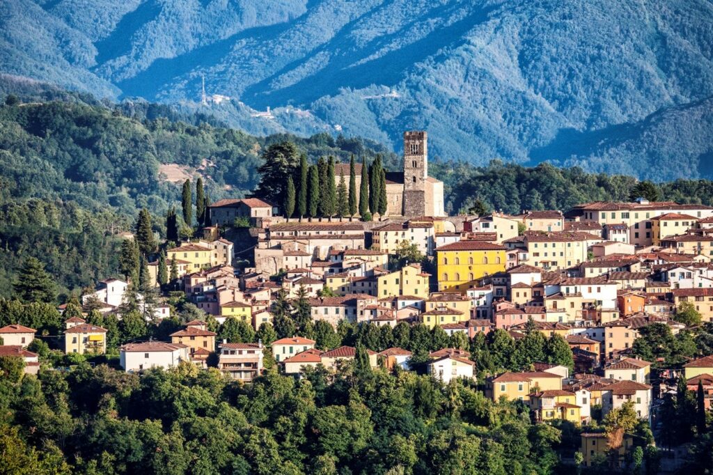 A view of the town of Barga, Tuscany, showing houses and a tower on a hilltop.